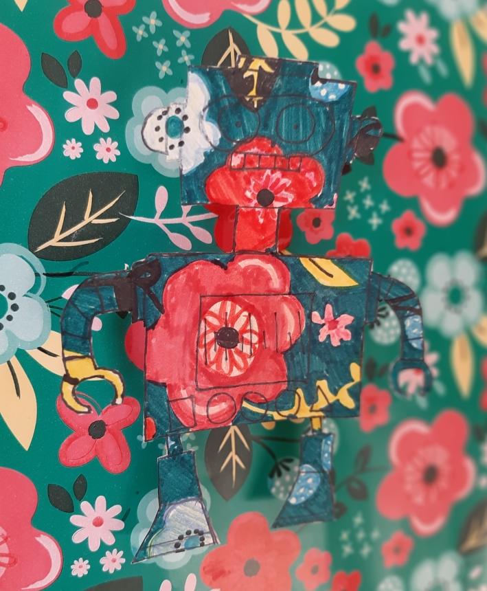 a child's art piece of a robot painted with red and white flowers on a floral background.