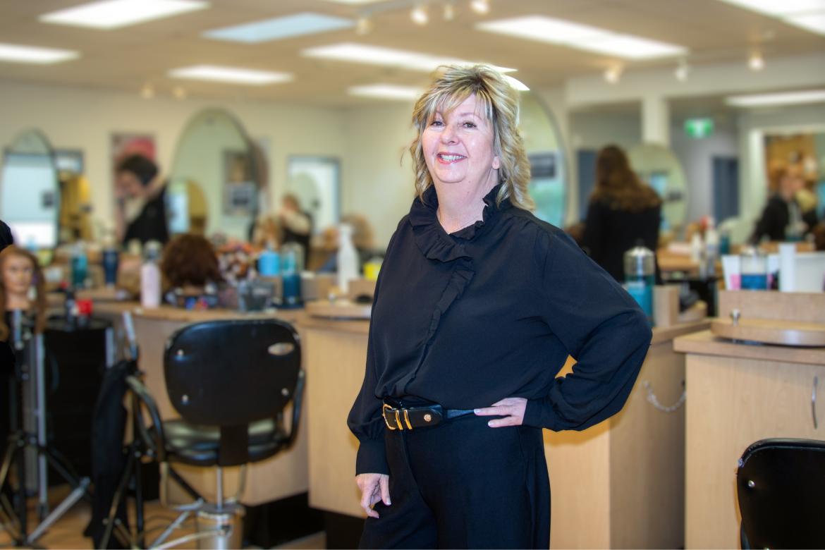 Dr. Sally Vinden stands inside a hair salon classroom