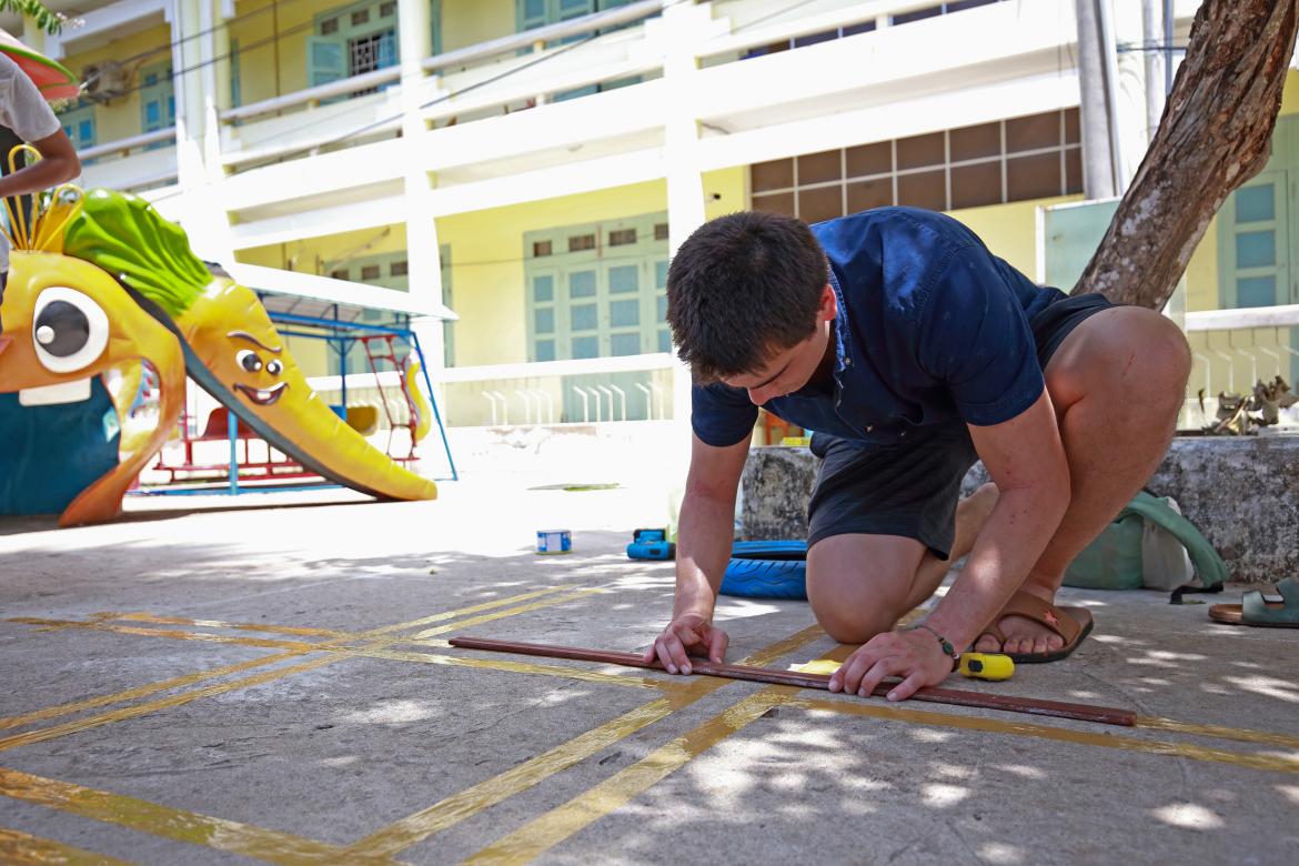 VIU Engineering student Michael Morris calculating the addition of playground equipment in Trà Vinh, Vietnam. VIU Engineering Filed School in Trà Vinh, Vietnam.