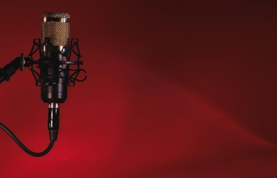 A podcast microphone in front of a red background.