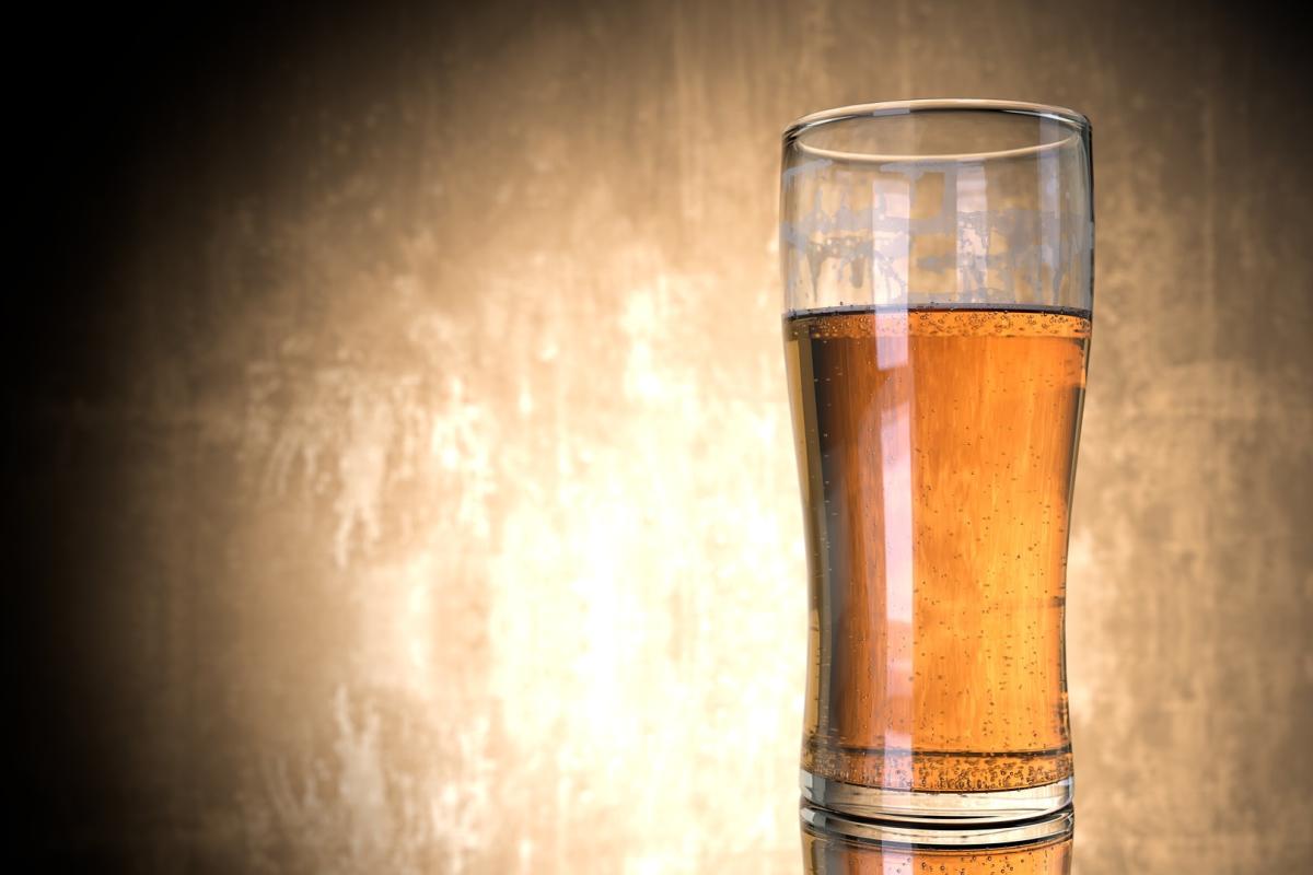 A glass of beer on a table in front of a tan an black background. Image featured in Dr. Marie Hopwood, VIU Department of Anthropology, Archaeology Beer blog