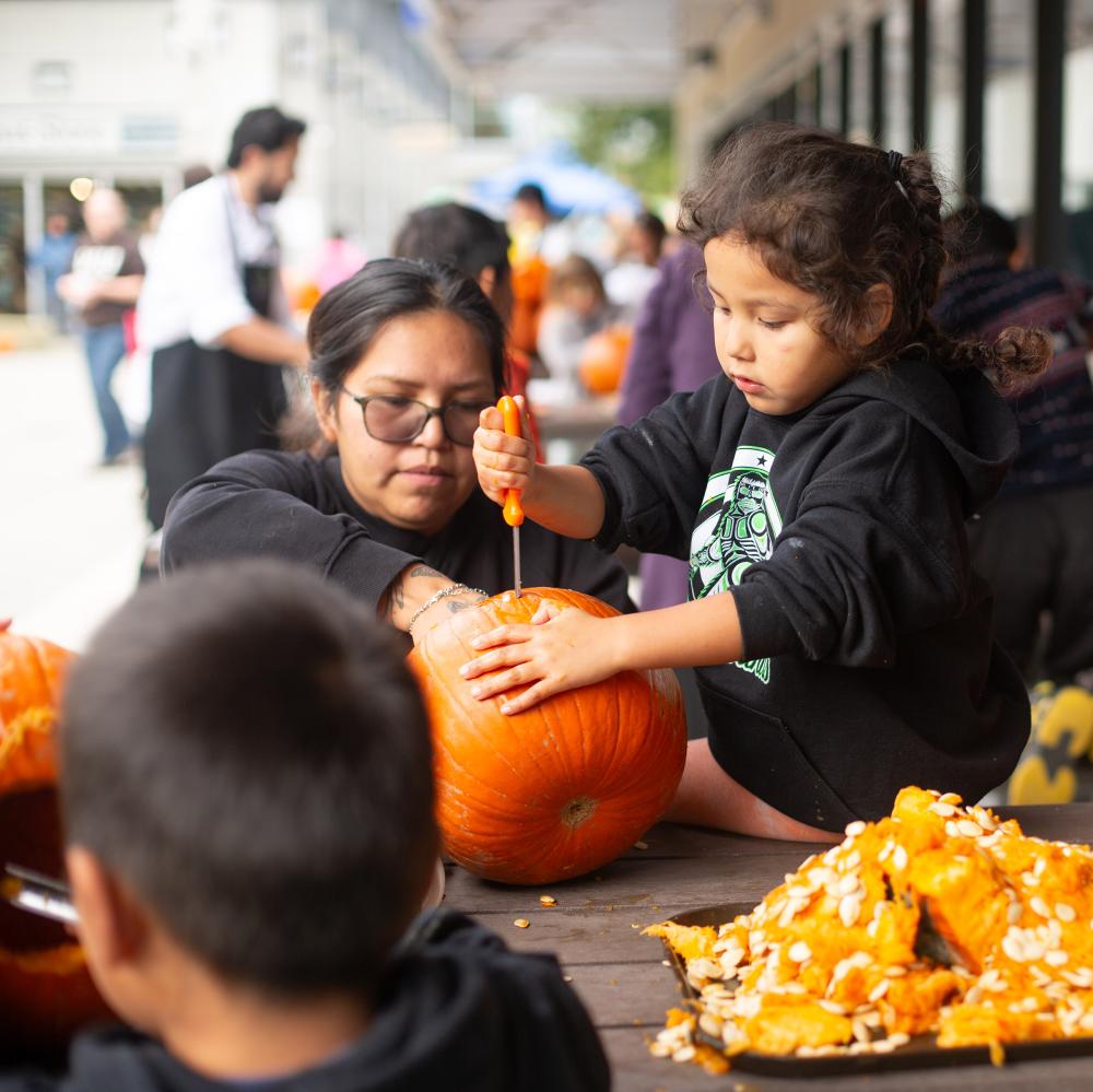 A group of kids carve pumpkins together