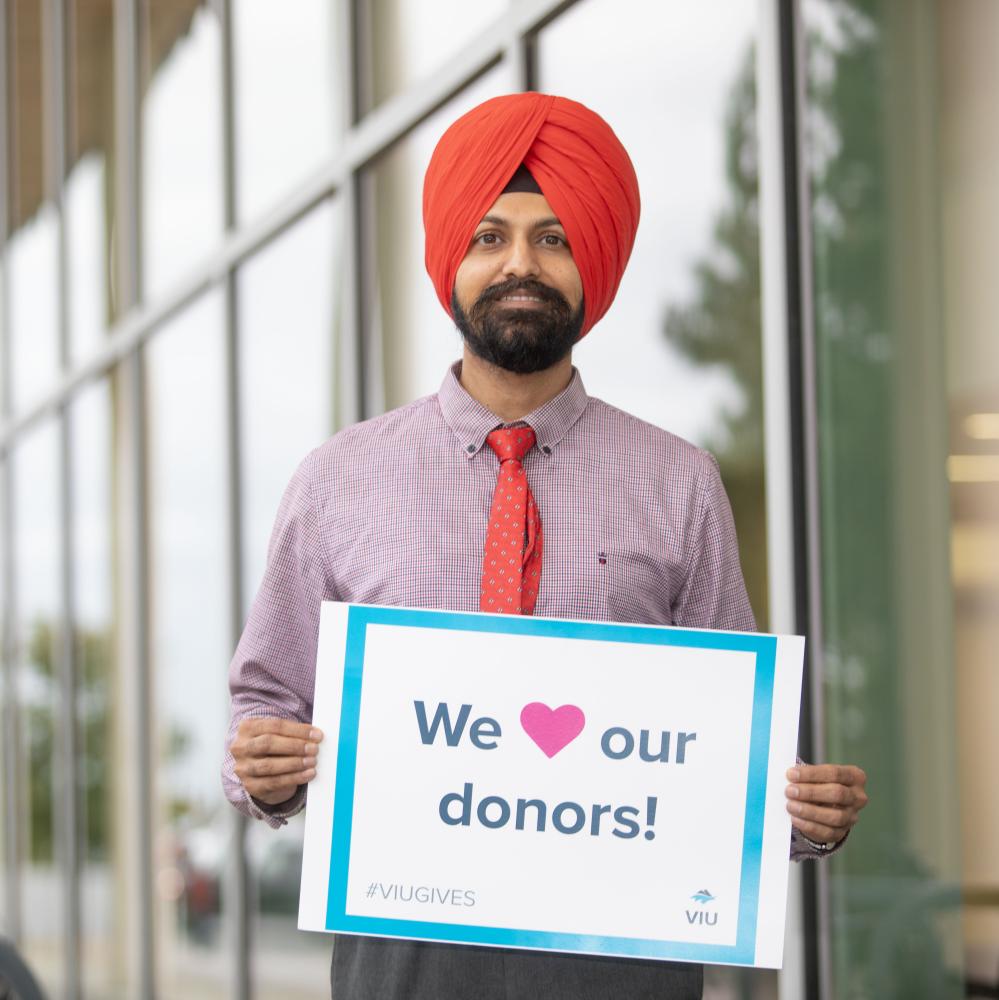 Harpreet outside the Centre for Health and Science holding a sign that reads We love our donors! 